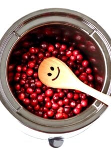 Fresh cranberries in crockpot cooking to make cranberry sauce.