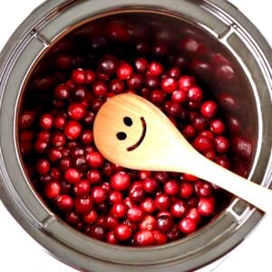 Fresh cranberries in crockpot cooking to make cranberry sauce.