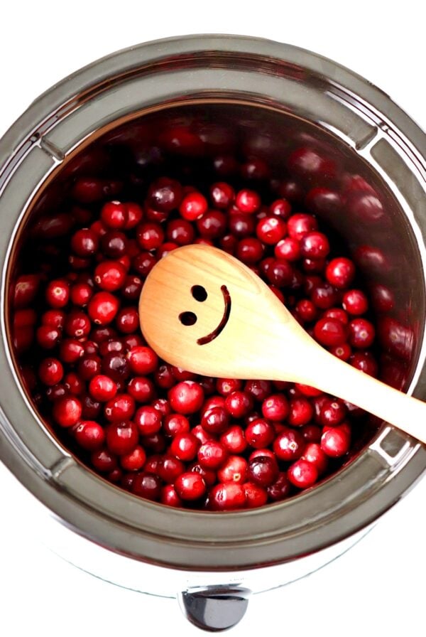 Fresh cranberries in crockpot cooking to make cranberry sauce.