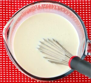 Homemade coffee creamer in large measuring cup with whisk.