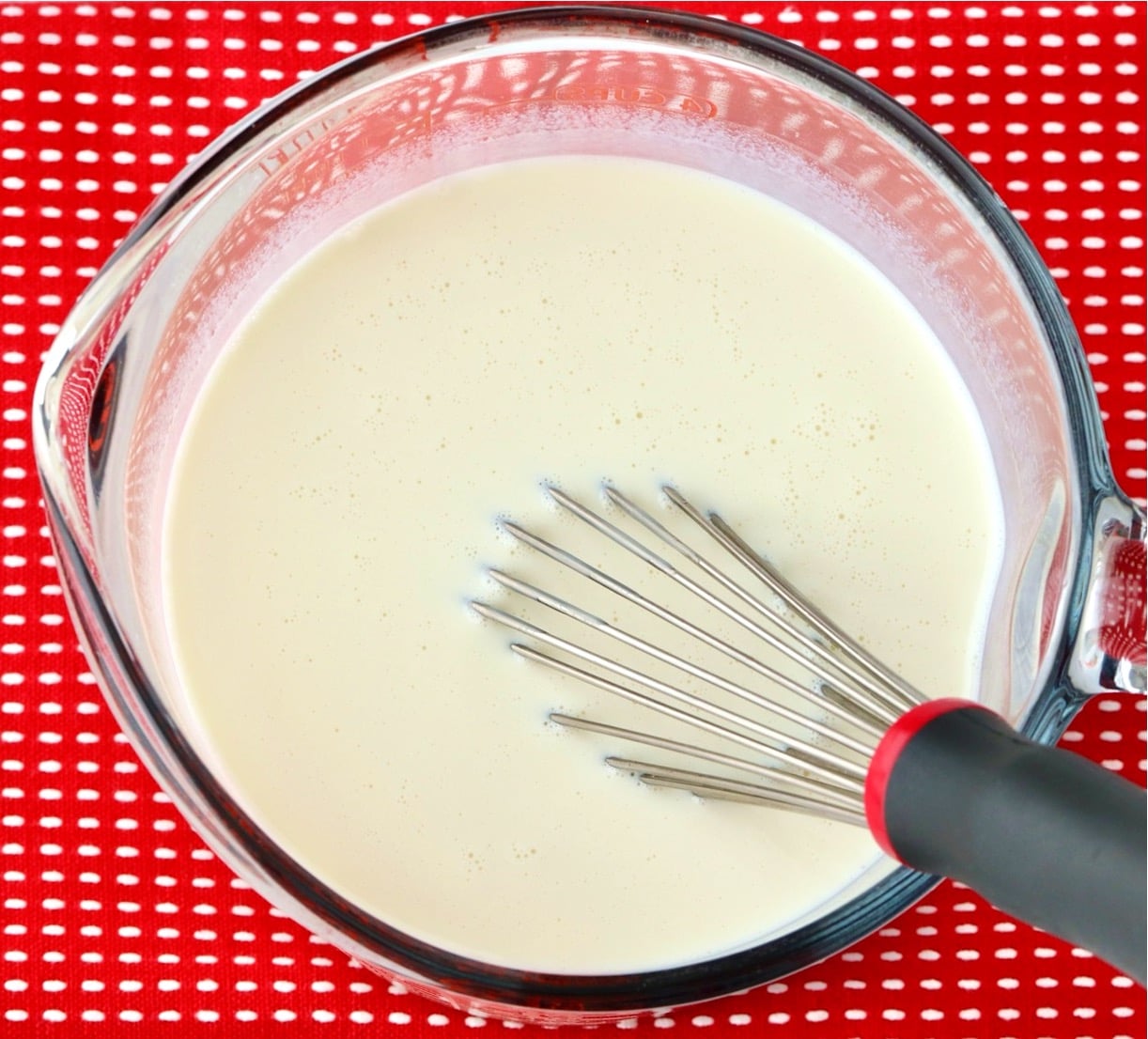 Homemade coffee creamer in large measuring cup with whisk.