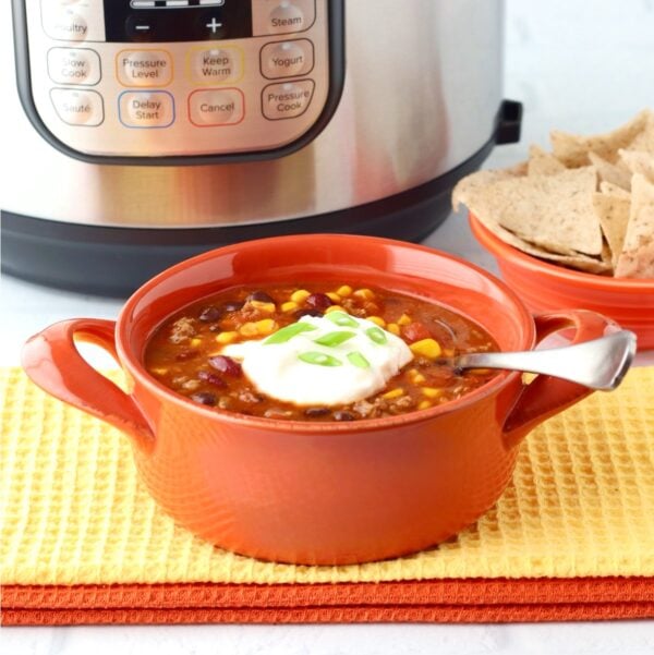 Taco soup with ground beef in bowl, and instant pot in background.