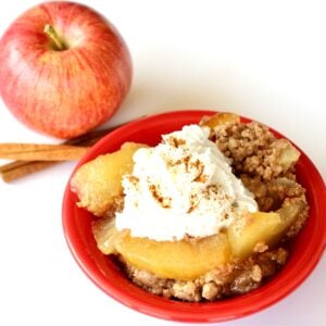 Apple spice dump cake in small bowl with whip cream on top.
