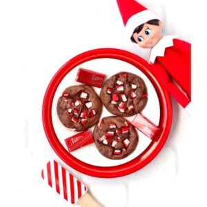 Elf looking at chocolate Christmas cookies on plate.