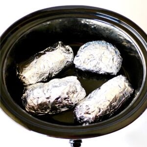 Sweet potatoes wrapped in foil in crockpot.