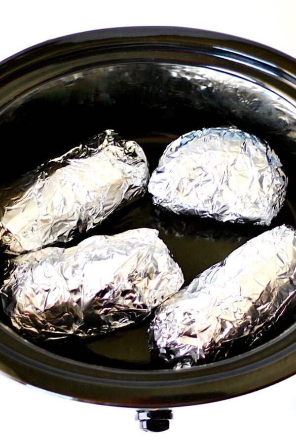Sweet potatoes wrapped in foil in crockpot.