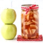Homemade apple pie filling in mason jar, with two Granny Smith apples to the side.