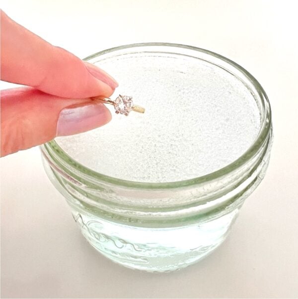 Diamond ring being placed into homemade diy jewelry cleaner solution.