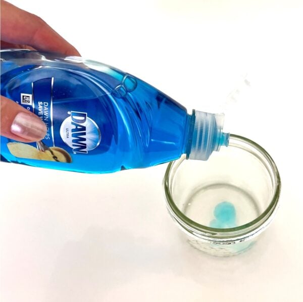 Dawn dish soap being poured into mason jar for diamond ring cleaning solution.